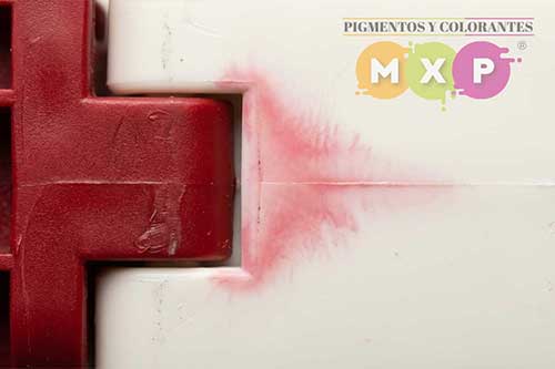 Defecto de migración de color en plásticos: pieza roja transfiriendo pigmento y manchando una superficie blanca adyacente debido al sangrado (bleeding) | MXP